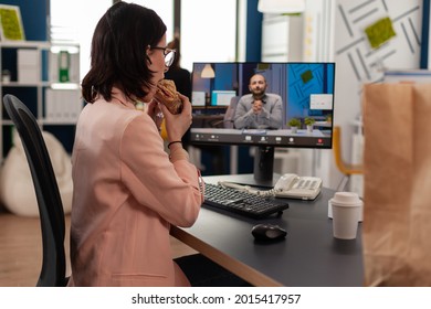 Entrepreneur Woman Sitting At Desk In Company Office Eating Sandwich During Online Videocall Conference Meeting Discussing Financial Strategy. Takeout Order Food Delivery In Corporate Job Place