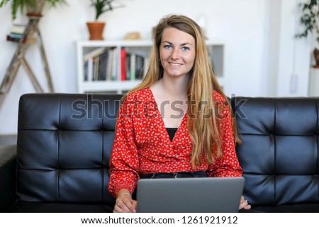 Similar – Entrepreneur woman wearing red shirt working with a laptop sitting on a couch at home