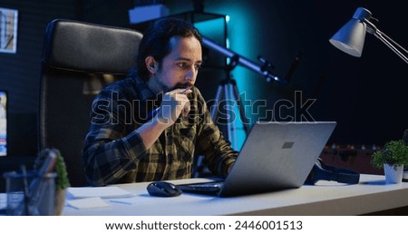 Entrepreneur working from home, using laptop and writing notes on paper. Remote worker in personal apartment office answering emails and transcribing important info on notepad