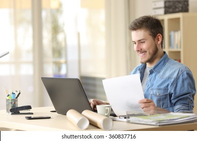 Entrepreneur working with a laptop and holding a document in a little office or home - Powered by Shutterstock