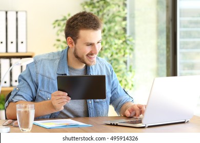 Entrepreneur working on line with a tablet and laptop in a desktop at office - Shutterstock ID 495914326