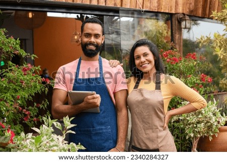 Entrepreneurial couple look at camera and smile in landscaping shop