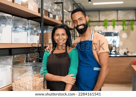 Entrepreneurial couple looks at camera and smiles in grocery store