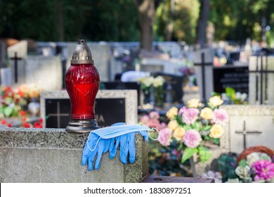 Entry to the cemetery wearing the obligatory protective mask and gloves against the coronavirus COVID-19 SARS-CoV-2. They are lying on the tombstone.