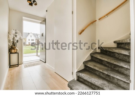 an entry way leading to the home's front door, with stairs and plants in vases on either side