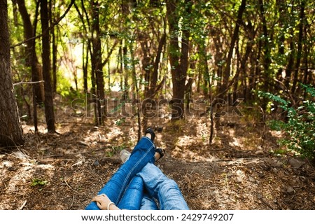 Entwined legs of a couple sitting together in the woods. Legs of a couple in the blue jeans in the forest.