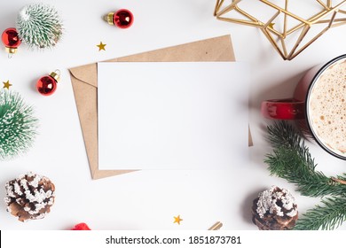 Envelop with blank of Christmas greeting card. Flat lay of white working table background with cup of coffee and Christmas decoration. Top view and copy space.