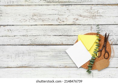 Envelope with blank card, scissors and eucalyptus branch on white wooden background