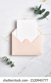 Envelope with greeting card mockup and eucalyptus plant on stone table. RSVP, wedding invitation card deisgn