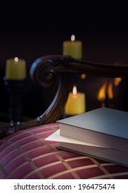 Envelope inserted into a book as a marker and left abandoned on a carved chair with firelight and candles in background to give a warm cozy winter feeling
