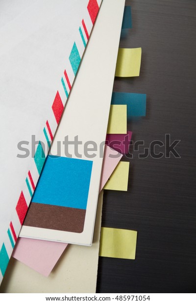 Envelopes, sticky notes,\
notepads, and notes all with small market tabs arranged on a chrome\
background