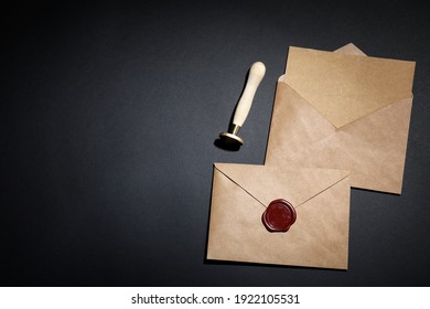 Envelopes with wax seal and stamp on black background, flat lay. Space for text