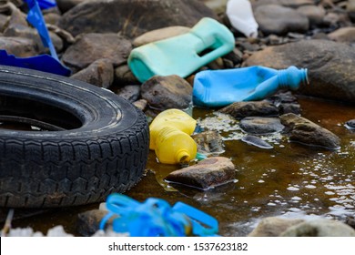 Enviromental Pollution. Rubber Tire With Plastic Waste In Dirty Water.