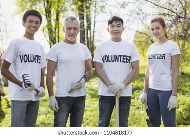 Environment sector. Energetic four volunteers standing and holding garden tools