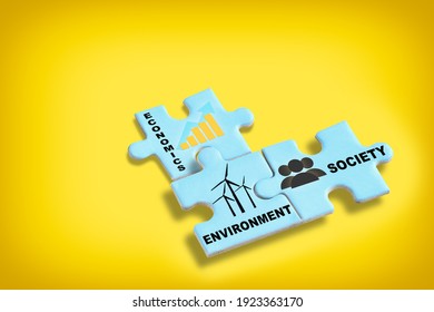 Environment society and economics written on blue puzzle jigsaw with shadow on yellow background. Sustainable development concept and future ahead idea
