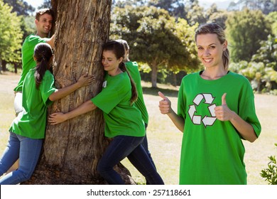 Environmental activists hugging a tree in the park on a sunny day - Powered by Shutterstock