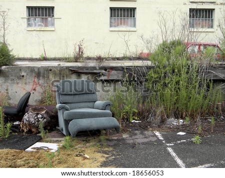 Environmental blight: old furniture discarded in an old parking lot outside a disused building