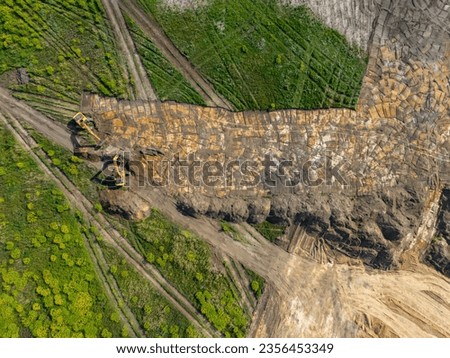 Environmental degradation, land preparation for development. Using heavy construction equipment. Green areas transformed into industrial buildings. Aerial view.