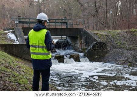 Environmental engineer checking water flow near a hydro dam. Biologist analyzes water quality and chemical composition for resource monitoring. Testing the chemical flow rate for environmental control