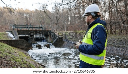 Environmental engineer checking water flow near a hydro dam. Biologist analyzes water quality and chemical composition for resource monitoring. Testing the chemical flow rate for environmental control