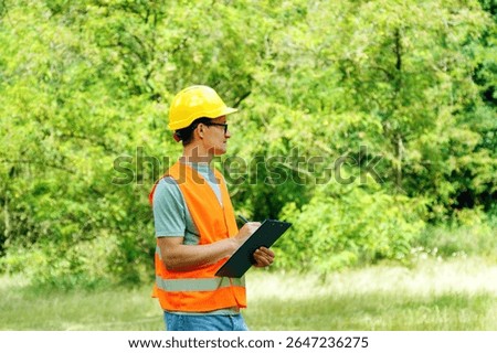 Environmental engineer man in the forest notes the environmental situation. Environmental technician with a tablet checks the trees. Forester worker.