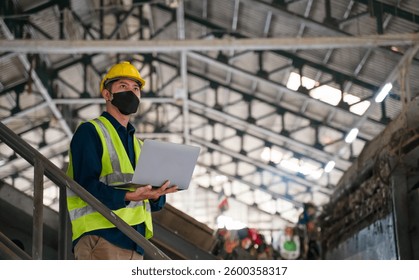 An environmental engineer in safety gear analyzes waste management data on a laptop while inspecting a recycling facility for efficiency and compliance.