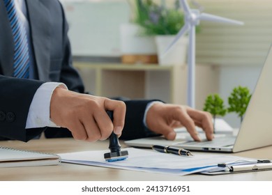 Environmental engineer signs approval for green business.Wind turbine models and green renewable energy and sustainability. Ecosystem and Organization Development Cooperation. - Powered by Shutterstock