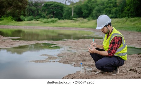 Environmental engineer Sit down next to a well and take note while holding the glass tube in his left hand to analysing check the quality and contaminants in the water source.