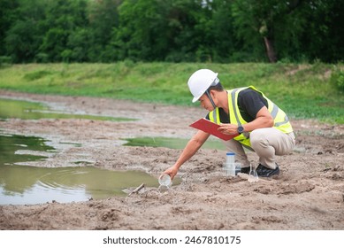 Environmental engineer Sit down next to a well and try to scoop water in plastic glass to analysing check the quality and contaminants in the water source.