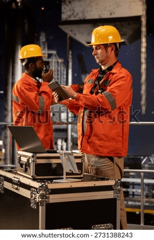 Environmental engineer uses tablet on offshore rig under the northern lights, ensuring petroleum and fuel extraction on the platform. Compliance with oil and gas production industry.
