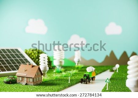 Environmental friendly toy town with model house, CFL lamps as trees and tractor carrying a light bulb