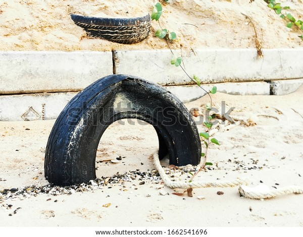 Environmental issue of\
waster form automobile: the damaged part of automobile tires on the\
beach in the sea 