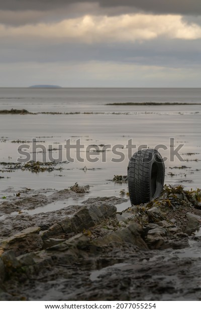 Environmental pollution in the ocean with a car\
tyre on the beach