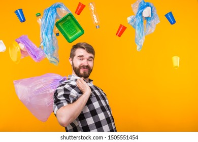 Environmental pollution, plastic recycling problem and waste disposal concept - funny man holding garbage bag on yellow background.