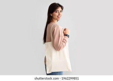 Environmental Protection. Portrait of smiling woman standing with blank canvas tote bag, free copy space for design mockup, isolated on studio background wall. Handmade female shopping bag