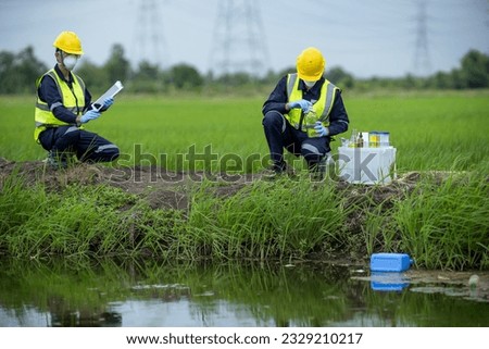 Environmental researchers investigate the condition of canal water for toxic spills, river waste water sampling, Asian researchers collect water samples in farmland for research and development.