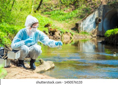 Environmental Scientist With A Flask Takes A Sample Of Water At The Site Of Industrial Discharge Of Water