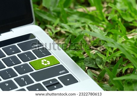 environmental technology concept.green recycle button on a black keyboard on green grass. Recycle zero waste ecology saving technology. Circular technology for digital and environmental sustainability
