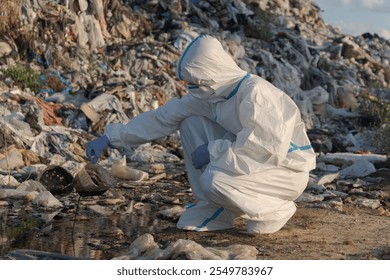 An environmental worker in protective gear carefully inspects polluted water at a landfill. The area is filled with plastic debris, reflecting concerns about waste and sanitation. - Powered by Shutterstock