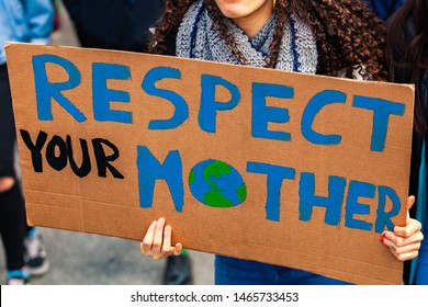 Environmentalist Sign At Climate Rally. A Close Up Shot Of A Homemade Cardboard Poster, Saying Respect Our Mother, Held By A Woman During A Street Protest For Environmental Issues.