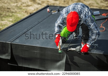EPDM Membrane Installation on Top of a Garden Shed. Professional Worker Attaching Pieces of Material Using air Blower.