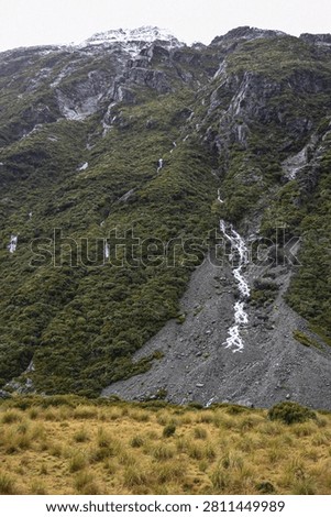 Ephemeral waterfalls cascade down the rugged cliffs after rainy weather in Aoraki Mt Cook National Park.