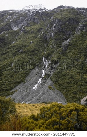 Ephemeral waterfalls cascade down the rugged cliffs after rainy weather in Aoraki Mt Cook National Park.