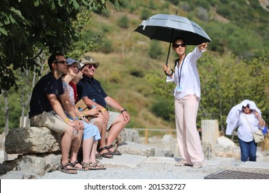 EPHESUS, TURKEY - June, 06, 2014: A group of tourists gather around a tour guide in the celsus library area of Ephesus in order to hear the guide tell them about the site.