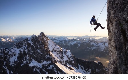 Epic Adventurous Extreme Sport Composite of Rock Climbing Man Rappelling from a Cliff. Mountain Landscape Background from British Columbia, Canada. Concept: Explore, Hike, Adventure, Lifestyle - Powered by Shutterstock