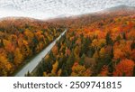 Epic Aerial Panorama of New England Road in Autumn. Car Drives on Road with Vast Forest of Colorful Fall Foliage Trip Tourism Scenic View Landscape