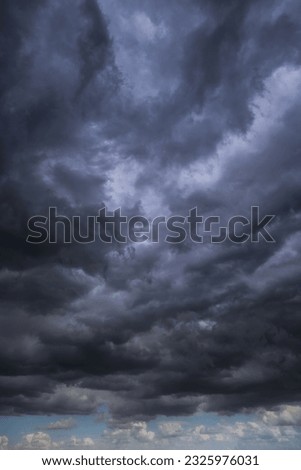 Epic Dramatic storm dark grey cumulus rain clouds against blue sky background texture, thunderstorm