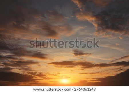 Epic dramatic sunset, sunrise on storm sky with dark clouds, orange yellow sun and sunlight background texture