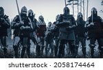 Epic Invading Army of Medieval Knights on Battlefield. Armored Soldiers in Helmets, With Shields and Swords ready for the Battle. War, Conquest, Crusade. Historical Reenactment.