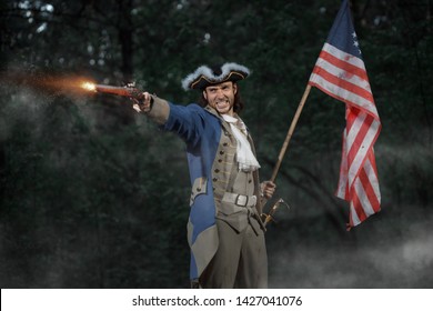 Epic Portrait Of Man Dressed As Soldier Of American Revolution War Of United States Aims From Pistol With Flag. 4 July Independence Day Of USA Concept Photo Composition: Soldier And Flag.